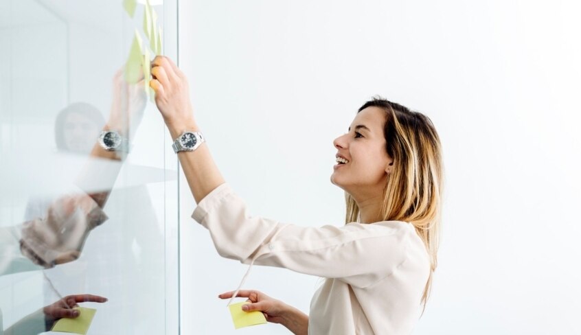 Eine Frau klebt Post-its an ein Whiteboard