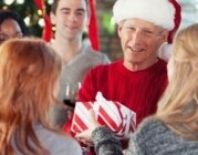 Mann mit roter Weihnachtsmütze bekommt Geschenk von Kolleginnen